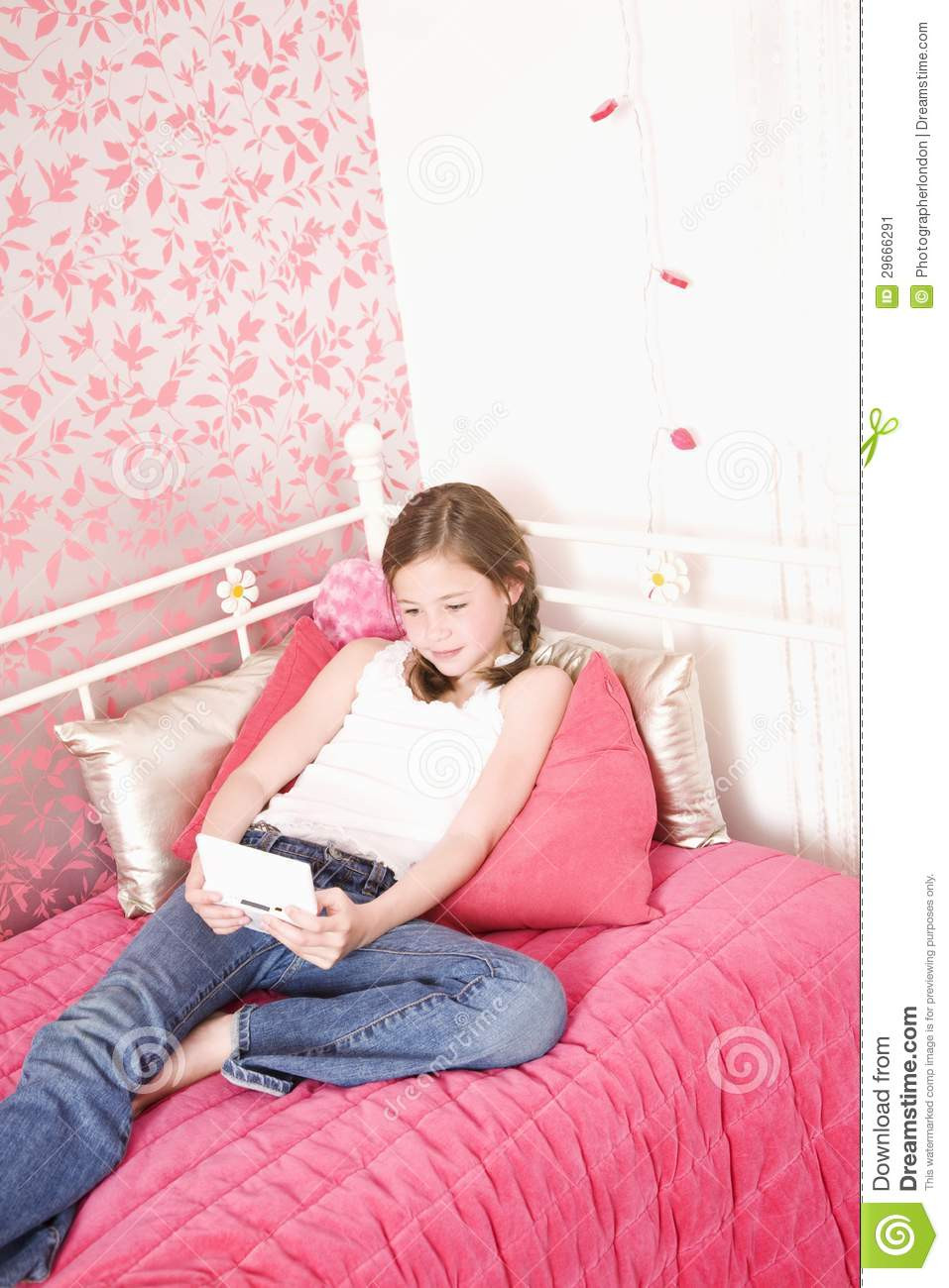 Girl In The Bedroom
 Young Girl In Bedroom Playing Handheld Game Stock Image